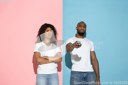 Image of Young emotional man and woman on pink and blue background