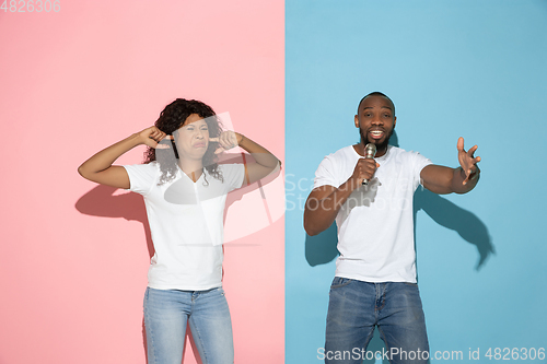 Image of Young emotional man and woman on pink and blue background