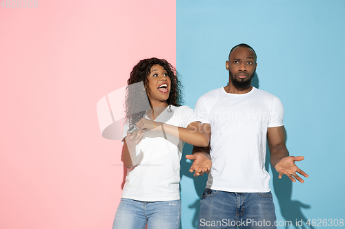 Image of Young emotional man and woman on pink and blue background