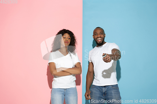 Image of Young emotional man and woman on pink and blue background