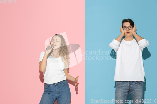 Image of Young emotional man and woman on pink and blue background