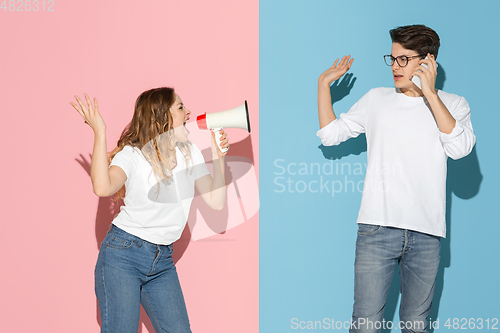 Image of Young emotional man and woman on pink and blue background