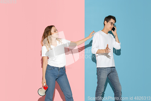 Image of Young emotional man and woman on pink and blue background