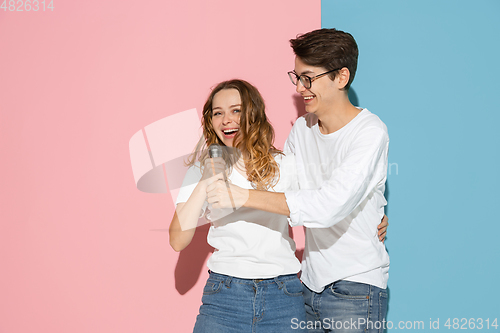 Image of Young emotional man and woman on pink and blue background