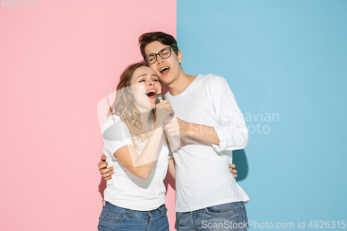 Image of Young emotional man and woman on pink and blue background