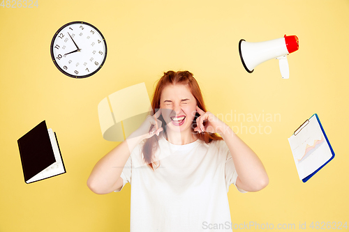 Image of Caucasian young woman\'s portrait on yellow background, too much tasks