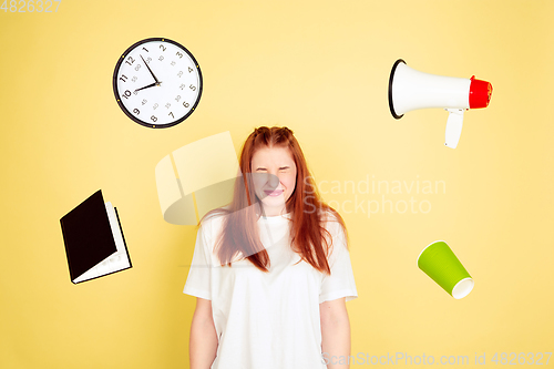 Image of Caucasian young woman\'s portrait on yellow background, too much tasks