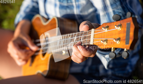 Image of Woman at sunset playing the ukulele