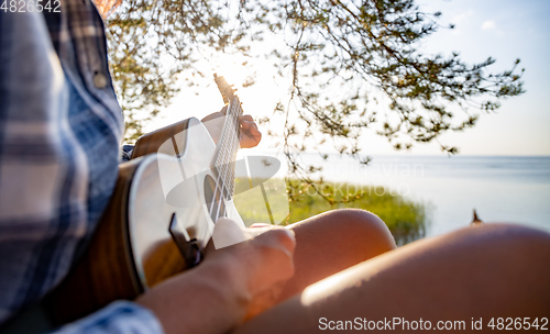 Image of Woman at sunset playing the ukulele