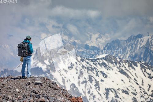 Image of Hiker woman standing up achieving the top. View at the snowy mou