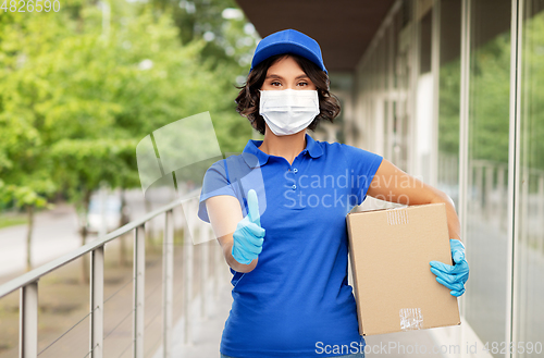 Image of delivery woman in mask holding parcel box outdoors