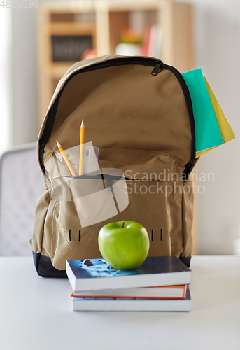 Image of school backpack with books and apple on table