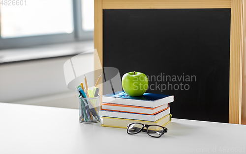 Image of books, apple and school supplies on table at home