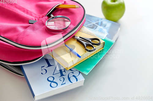 Image of backpack with books, school supplies and apple