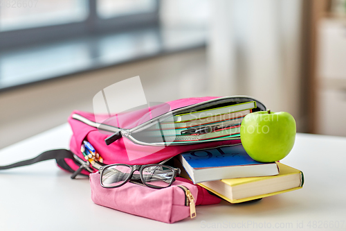 Image of backpack, apple and school supplies on table