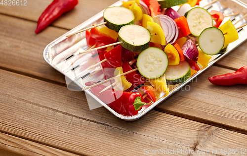 Image of close up of vegetables on skewers on foil grill