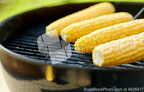 Image of close up of corn roasting on grill outdoors