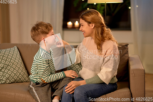 Image of happy mother touching little son's nose at home