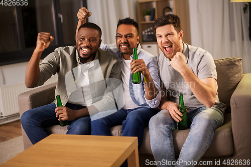 Image of happy male friends or fans drinking beer at home