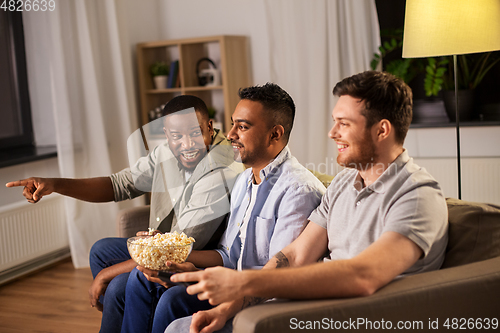 Image of male friends with popcorn watching tv at home