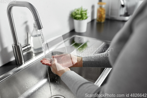 Image of woman washing hands with liquid soap in kitchen