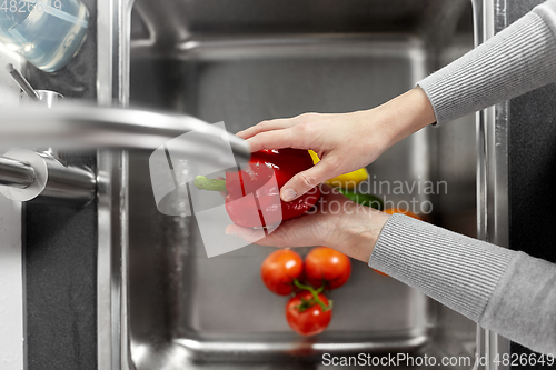 Image of woman washing fruits and vegetables in kitchen