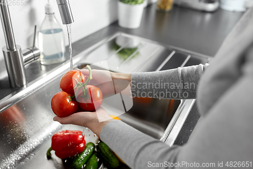 Image of close up of woman washing vegetables in kitchen