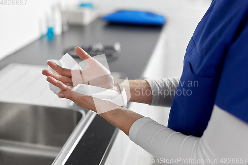 Image of doctor or nurse drying hands with paper tissue