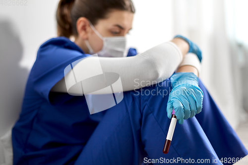 Image of sad doctor or nurse holding beaker with blood test