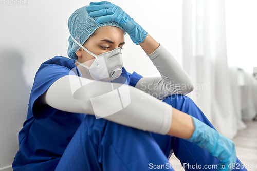 Image of sad doctor or nurse in face mask holding to head