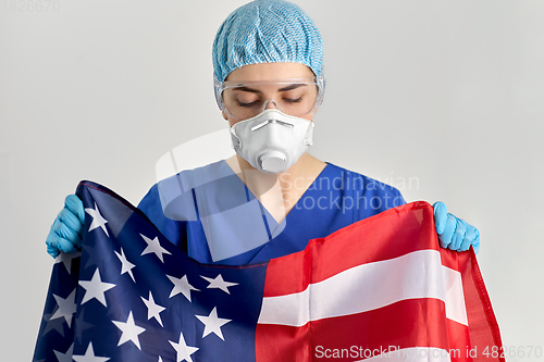 Image of doctor in goggles and mask holding flag of america