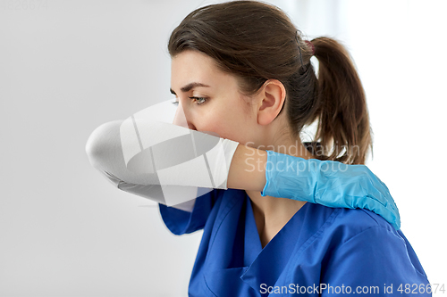 Image of doctor or nurse coughing covering mouth with elbow