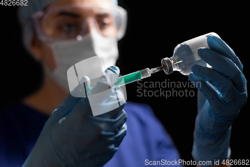 Image of doctor in face mask with syringe and medicine