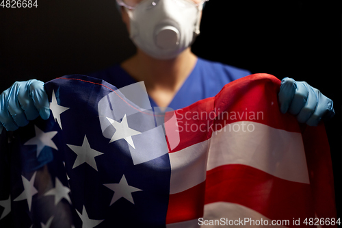 Image of doctor in goggles and mask holding flag of america