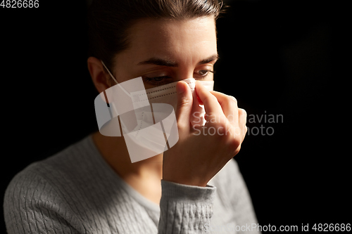Image of sick woman adjusting protective medical face mask