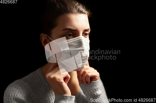 Image of sick woman adjusting protective medical face mask