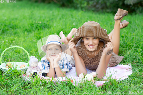 Image of Little boy and teen age girl having picnic outdoors
