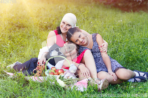 Image of mother with two kids having picnic outdoors