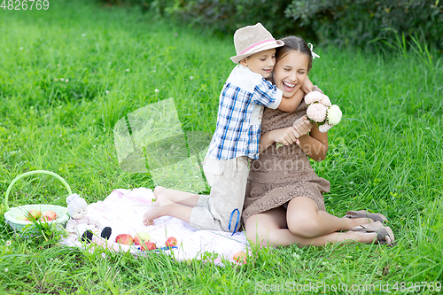 Image of Little boy and teen age girl having picnic outdoors