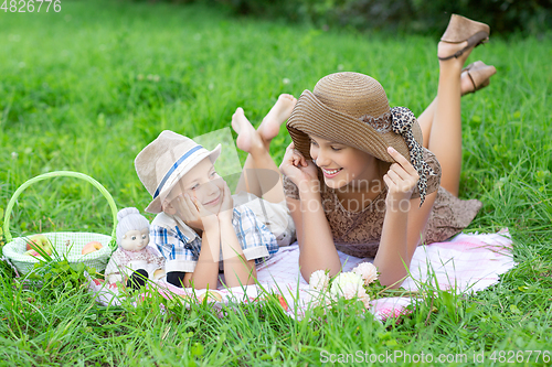 Image of Little boy and teen age girl having picnic outdoors