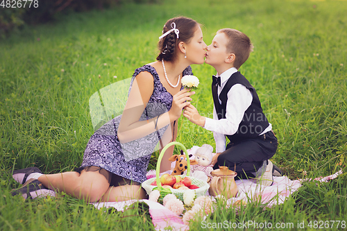 Image of Little boy and teen age girl having picnic outdoors