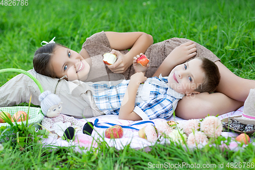 Image of Little boy and teen age girl having picnic outdoors