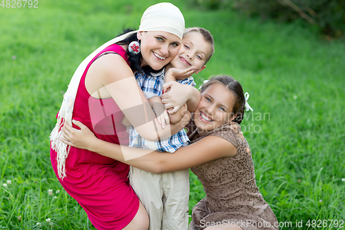 Image of mother with two kids having picnic outdoors