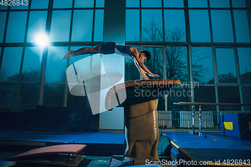 Image of Little male gymnast training in gym, flexible and active