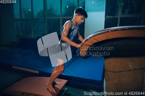 Image of Little male gymnast training in gym, flexible and active