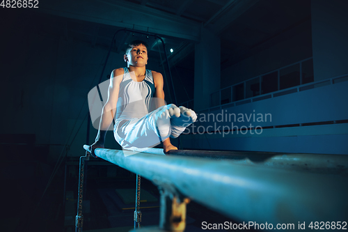 Image of Little male gymnast training in gym, flexible and active