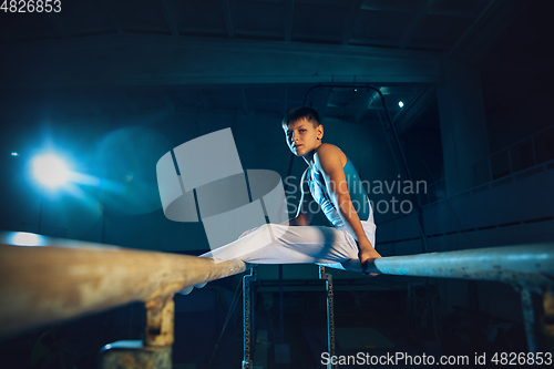 Image of Little male gymnast training in gym, flexible and active