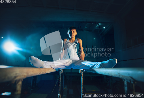 Image of Little male gymnast training in gym, flexible and active