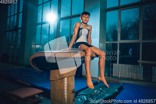 Image of Little male gymnast training in gym, flexible and active