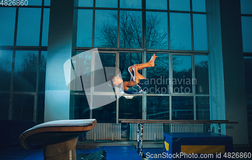 Image of Little male gymnast training in gym, flexible and active